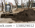 A small bulldozer on wheels unloads soil for a lawn. 138029012