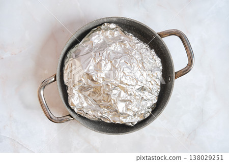 Cooking pork shoulder in a pot covered with foil for slow roasting Cooking pork shoulder in a pot covered with foil for slow roasting 138029251