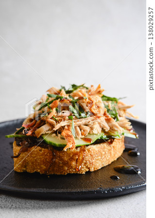 Pulled pork toast topped with caramelized onions and fresh herbs served on black plate Pulled pork toast topped with caramelized onions and fresh herbs served on black plate 138029257