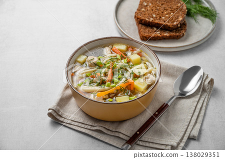 Chicken noodle soup with fresh dill in a bowl on a light textured background Chicken noodle soup with fresh dill in a bowl on a light textured background 138029351