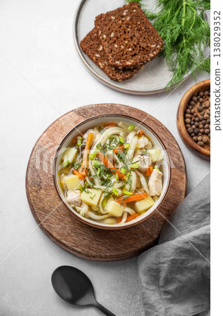 Chicken noodle soup with fresh dill in a bowl on a light textured background Chicken noodle soup with fresh dill in a bowl on a light textured background 138029352