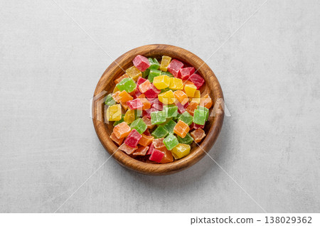 Candied mix fruit in a wooden bowl on a light textured background. Candied mix fruit in a wooden bowl on a light textured background. 138029362