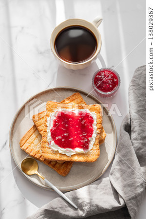 Toast with sweet berry-fruit jam and cream cheese on a plate on a white marble background Toast with sweet berry-fruit jam and cream cheese on a plate on a white marble background 138029367