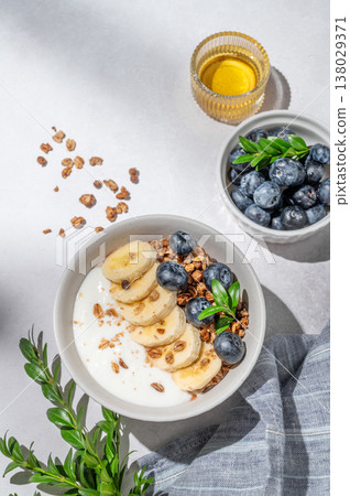 Natural greek yogurt with granola, blueberry and banana in a bowl on a light concrete background Natural greek yogurt with granola, blueberry and banana in a bowl on a light concrete background 138029371