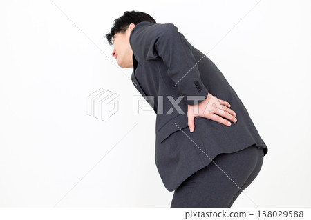 A middle-aged businessman in a suit suffering from lower back pain. A middle-aged businessman in a suit suffering from lower back pain. 138029588