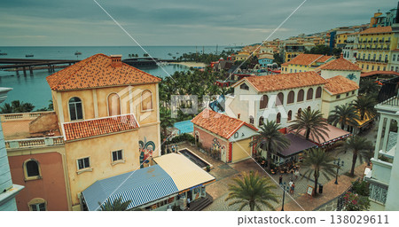 Narrow alleyway framing colonial buildings with stone arches, weathered facades, multi-level balconies, and turquoise harbor beyond, blending heritage charm and coastal beauty Narrow alleyway framing colonial buildings with stone arches, weathered facades, multi-level balconies, and turquoise harbor beyond, blending heritage charm and coastal beauty 138029611