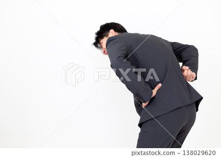 A middle-aged businessman in a suit suffering from lower back pain. 138029620