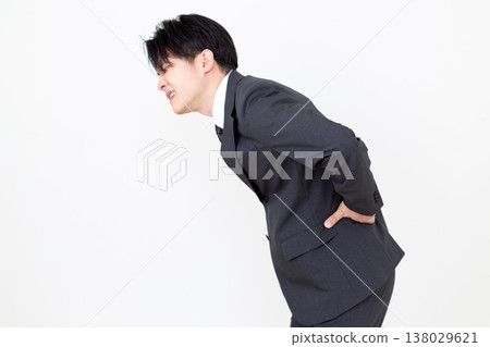 一位身穿西裝的中年商人,正遭受腰痛的困擾。 一位身穿西裝的中年商人,正遭受腰痛的困擾。 138029621