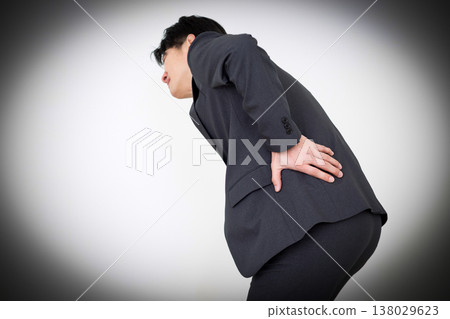 A middle-aged businessman in a suit suffering from lower back pain. 138029623