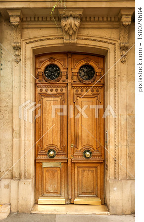 Old wooden door entrance on a classic stone building in Paris, France, showing intricate carvings and vintage details 138029684