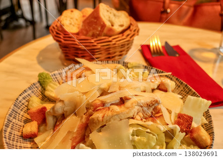 Caesar salad with grilled chicken, parmesan, crunchy croutons, and fresh lettuce, served with bread in a Parisian restaurant 138029691