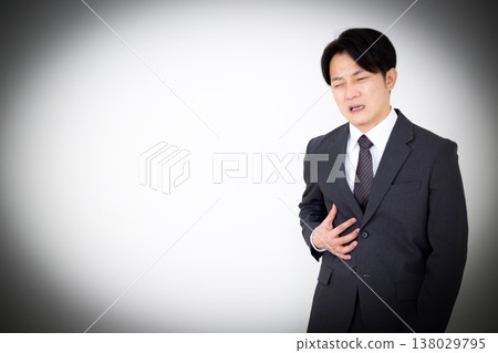 A middle-aged businessman in a suit suffering from pain in his right side. 138029795