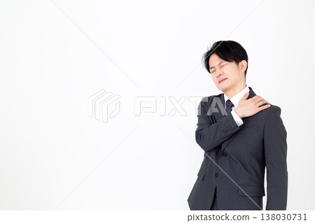 A middle-aged male businessman in a suit suffering from stiff shoulders A middle-aged male businessman in a suit suffering from stiff shoulders 138030731