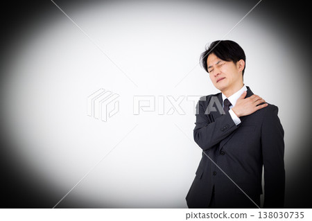 A middle-aged male businessman in a suit suffering from stiff shoulders 138030735