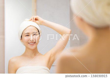 A woman doing hair care in the bathroom. 138030915