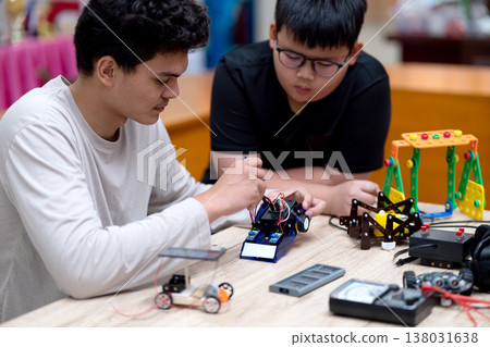 young man and a boy studying electronic assembly as an experiment for robotic young man and a boy studying electronic assembly as an experiment for robotic 138031638
