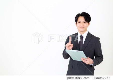 A middle-aged businessman holding a binder and raising his index finger. A middle-aged businessman holding a binder and raising his index finger. 138032258