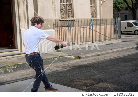 Happy student celebrating high school graduation, spraying champagne outdoors with exuberant joy and energy after passing final exams, marking a proud new chapter and freedom 138032322