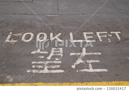 Look Left bilingual pedestrian safety warning painted on Hong Kong sidewalk pavement in Chinese English 138032417