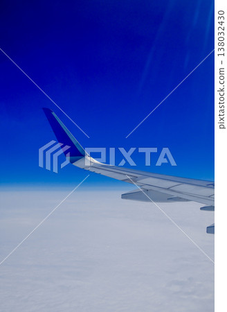 Airplane wing over white clouds with vivid blue sky horizon view from passenger window during flight Airplane wing over white clouds with vivid blue sky horizon view from passenger window during flight 138032430