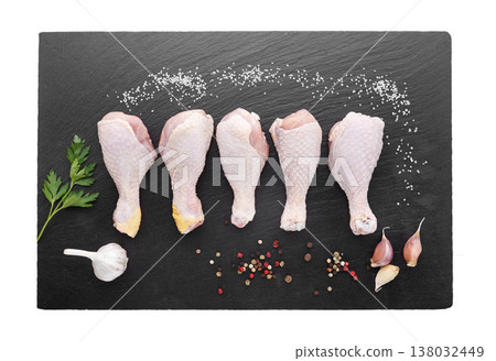 Raw chicken drumsticks arranged on black slate board with garlic, pepper, salt and parsley. Raw chicken drumsticks arranged on black slate board with garlic, pepper, salt and parsley. 138032449