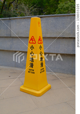 Yellow traffic cone with Wet Floor text against concrete wall in Hong Kong urban park 138033105