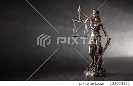 A bronze statue of Lady Justice on a dark, textured background with strong side lighting that highlights her details and symbolism. The composition, with free space on the left, is ideal for 138033131