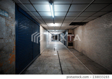The somber, symmetrical composition of the dimly lit corridors and tightly closed metal roller shutters of an old apartment building in Taipei. The somber, symmetrical composition of the dimly lit corridors and tightly closed metal roller shutters of an old apartment building in Taipei. 138033283