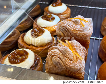 Layered pastries with cream topping and fruit jam in bakery showcase. Flaky texture, artisan baking, dessert selection, sweet treat concept Layered pastries with cream topping and fruit jam in bakery showcase. Flaky texture, artisan baking, dessert selection, sweet treat concept 138033874