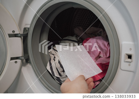 innovative color trap sheet close up in washing machine drum with pile of varied clothes innovative color trap sheet close up in washing machine drum with pile of varied clothes 138033933