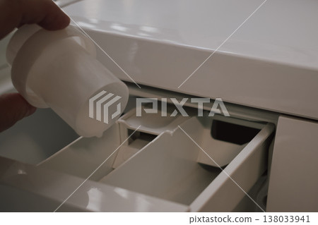 everyday domestic routine: hand preparing detergent and softener for the wash cycle everyday domestic routine: hand preparing detergent and softener for the wash cycle 138033941