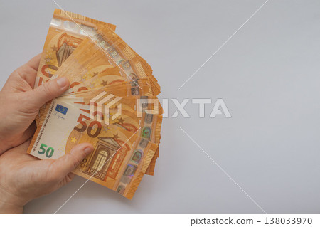 Female hands holding a large fan of 50 Euro banknotes against a white background. High-volume cash concept with orange bills and extensive copy space for design Female hands holding a large fan of 50 Euro banknotes against a white background. High-volume cash concept with orange bills and extensive copy space for design 138033970