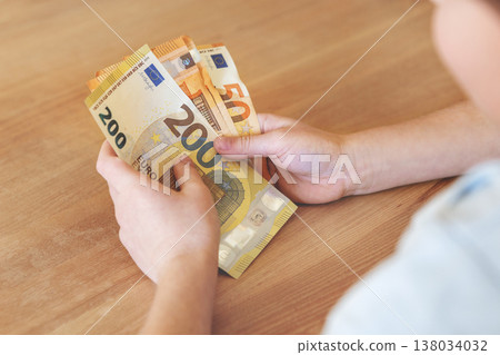 Close up hands holding euro banknotes, counting European cash money in natural light. Financial concept of income, savings, payment and budget management, economy and personal finance Close up hands holding euro banknotes, counting European cash money in natural light. Financial concept of income, savings, payment and budget management, economy and personal finance 138034032