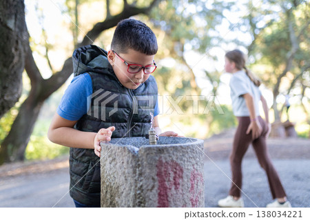 Boy drinking water from public park fountain Boy drinking water from public park fountain 138034221