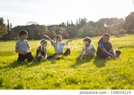 Group of children happily sitting playing on green grass Group of children happily sitting playing on green grass 138034224