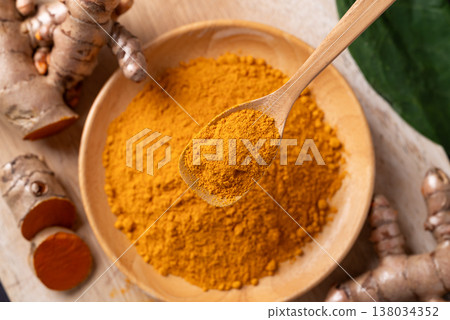 Turmeric powder and fresh turmeric roots on a wooden board. Organic healthy spice Turmeric powder and fresh turmeric roots on a wooden board. Organic healthy spice 138034352