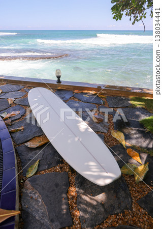 Surfboard on stone path by ocean Surfboard on stone path by ocean 138034441