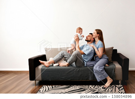 Family enjoys time together at home while playing with their baby and sharing moments of joy on a couch during a sunny afternoon Family enjoys time together at home while playing with their baby and sharing moments of joy on a couch during a sunny afternoon 138034896
