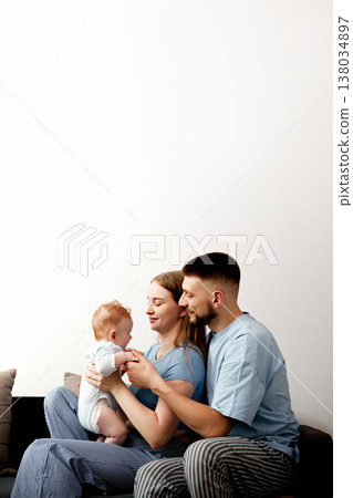 Family spends time together at home while playing with their baby on a sofa, enjoying a moment of joy and connection in the living room 138034897