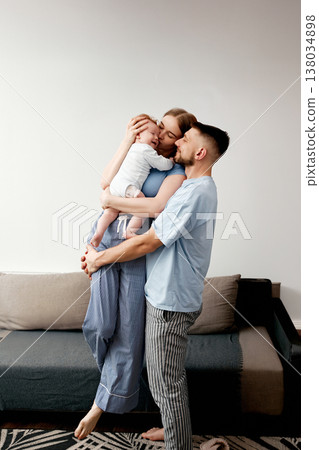 Family enjoys a moment together in a cozy living room at home while celebrating a special occasion with balloons above them 138034898