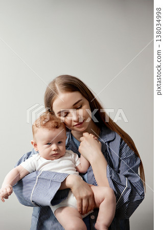 Loving mother holding her adorable baby in a cozy indoor setting, showcasing a tender moment of connection and affection, family bonding concept Loving mother holding her adorable baby in a cozy indoor setting, showcasing a tender moment of connection and affection, family bonding concept 138034998