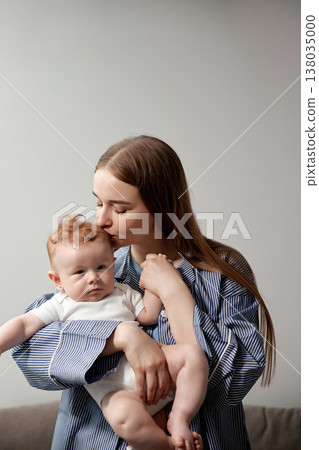 Loving mother gently kisses her baby while holding him in her arms, showcasing a tender moment of affection and connection between parent and child, family bonding concept Loving mother gently kisses her baby while holding him in her arms, showcasing a tender moment of affection and connection between parent and child, family bonding concept 138035000
