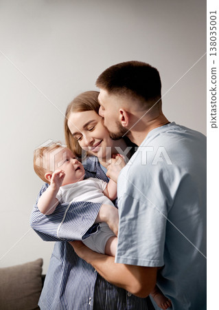 Joyful family moment with parents embracing their baby in a cozy home setting showcasing love and connection, family bonding concept Joyful family moment with parents embracing their baby in a cozy home setting showcasing love and connection, family bonding concept 138035001