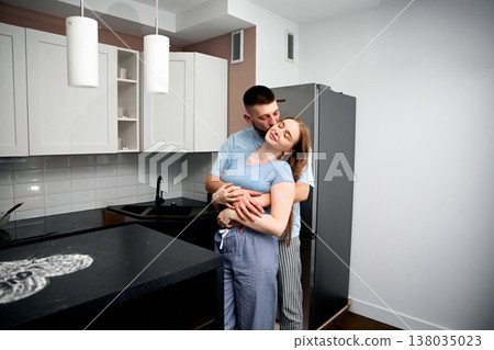 Couple enjoys a moment together in modern kitchen while sharing a warm embrace on a sunny morning 138035023