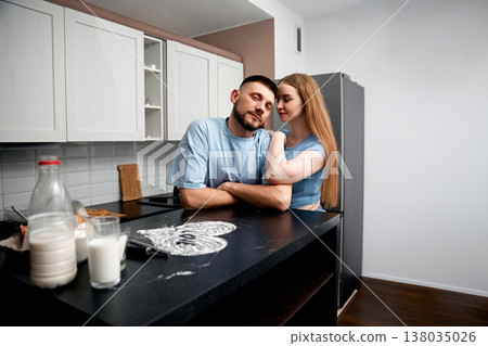 Couple sharing a moment in the kitchen while preparing food and enjoying their time together in an apartment 138035026