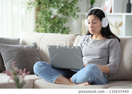 Perplexed asian woman watching media on personal computer 138035440