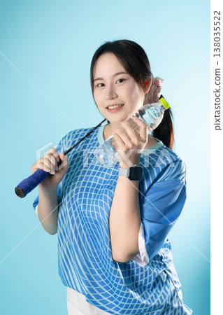 Happy smiling woman teen girl with badminton racket and water bottle portrait in studio action Happy smiling woman teen girl with badminton racket and water bottle portrait in studio action 138035522