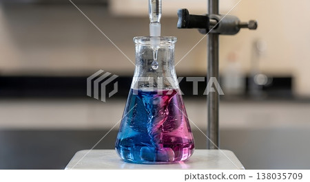 Vibrant chemistry experiment featuring blue and pink liquids in an erlenmeyer flask, creating a layered or gradient effect for science concepts 138035709