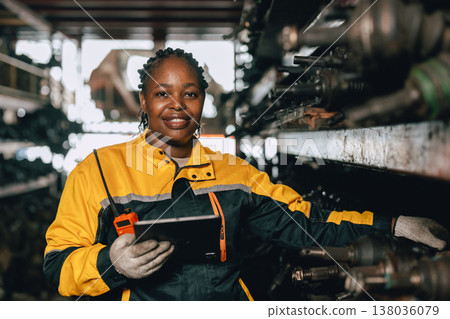 Happy Black African women engineer worker enjoy working in old used machine part stock warehouse. 138036079