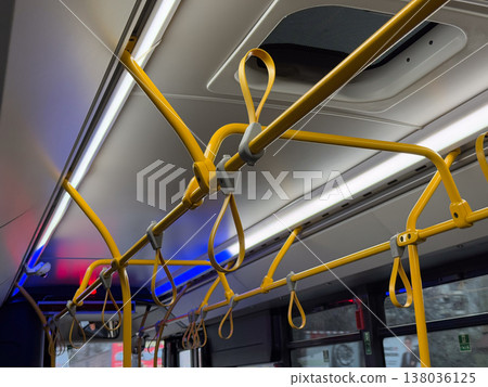 Close view of yellow handrails and hanging handles inside modern city bus. Passenger support system, safety grip design, public transport ergonomics, standing stability, movement control in transit Close view of yellow handrails and hanging handles inside modern city bus. Passenger support system, safety grip design, public transport ergonomics, standing stability, movement control in transit 138036125